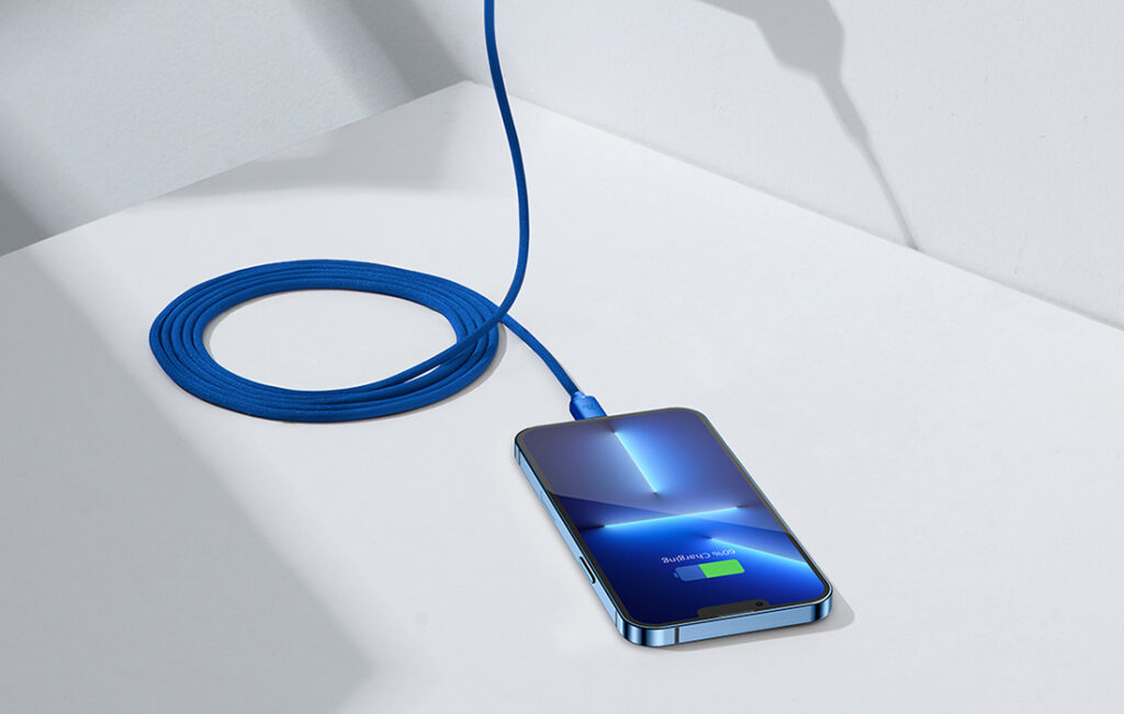 Blå USB-C till Lightning-kabel i tygmaterial med blå metallkontakt, ansluten till iPhone